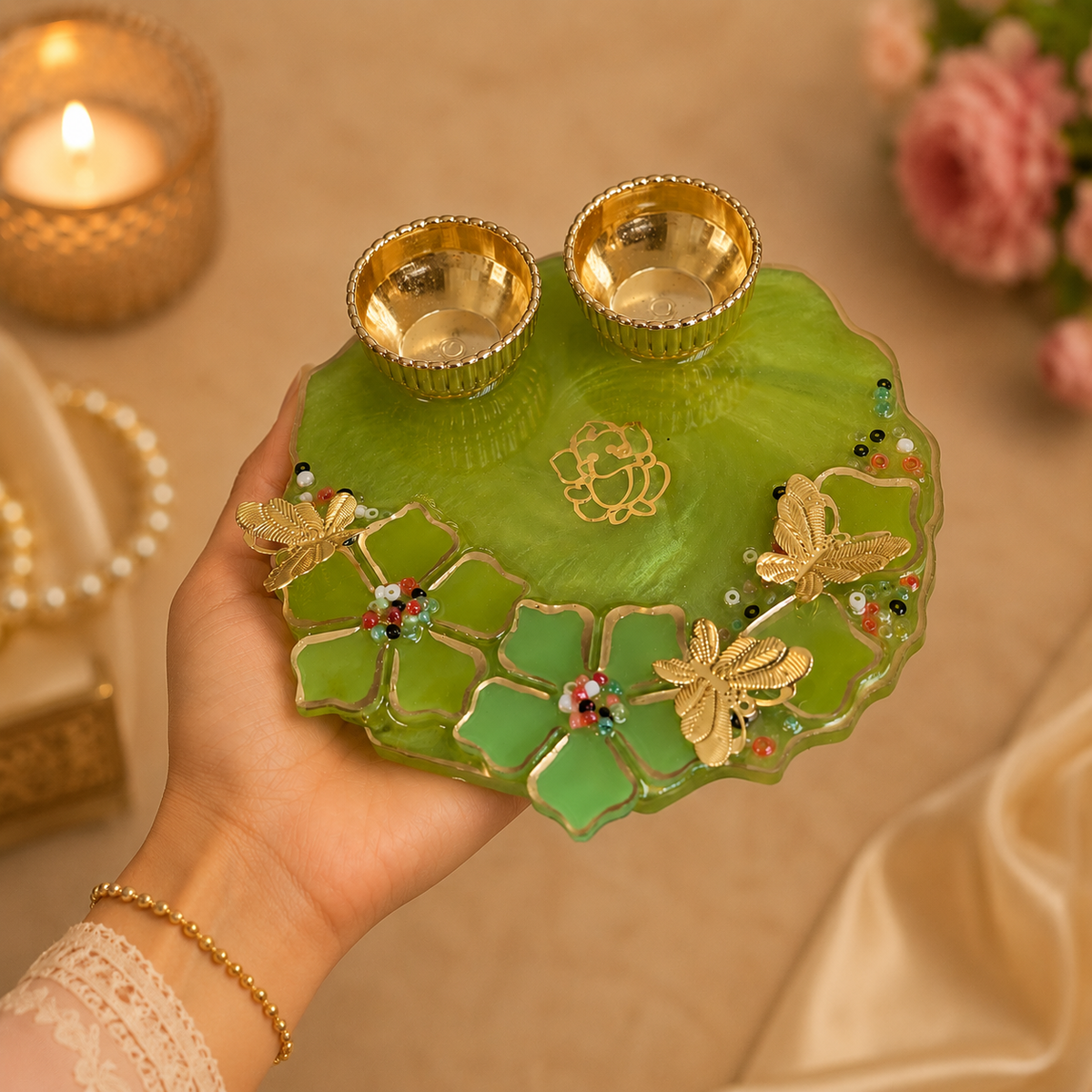 Hand holding a green decorative plate with gold accents and two small bowls, against a warm-toned background.