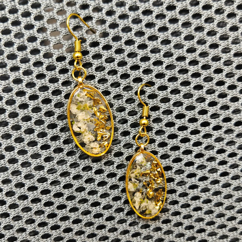 Gold earrings with embedded stones on a textured black and gray background