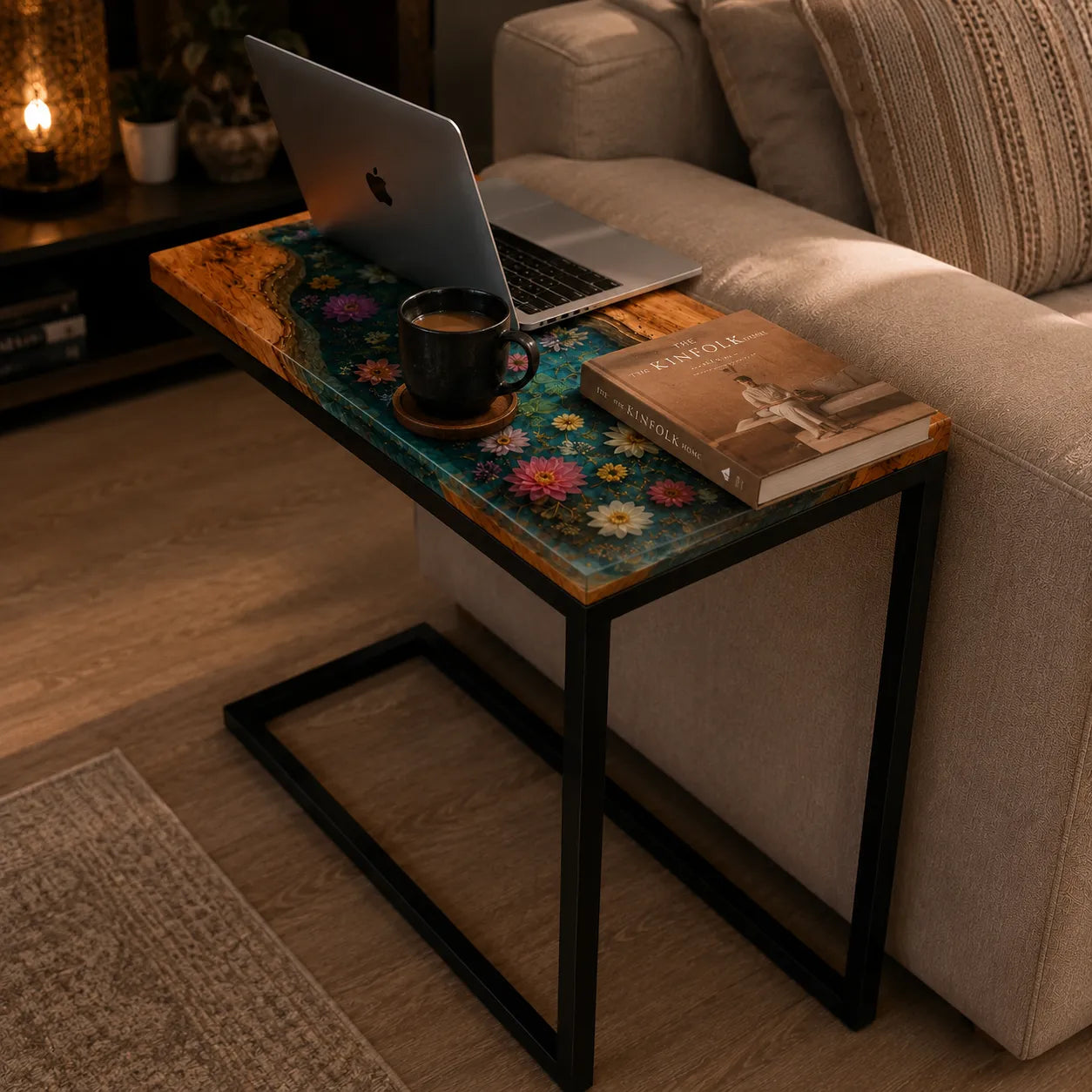 Small table with a laptop, coffee cup, and book next to a beige couch in a cozy living room.