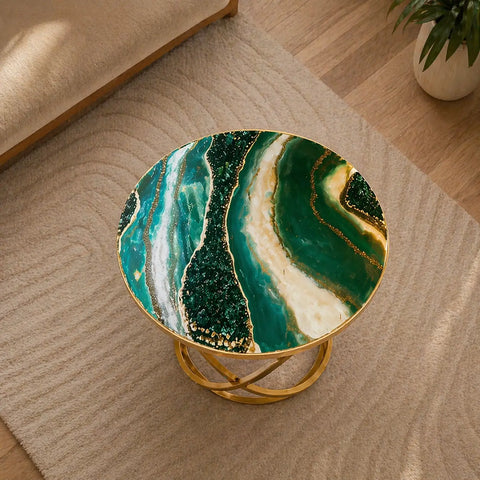 Round side table with green and gold marble design on a wooden floor.