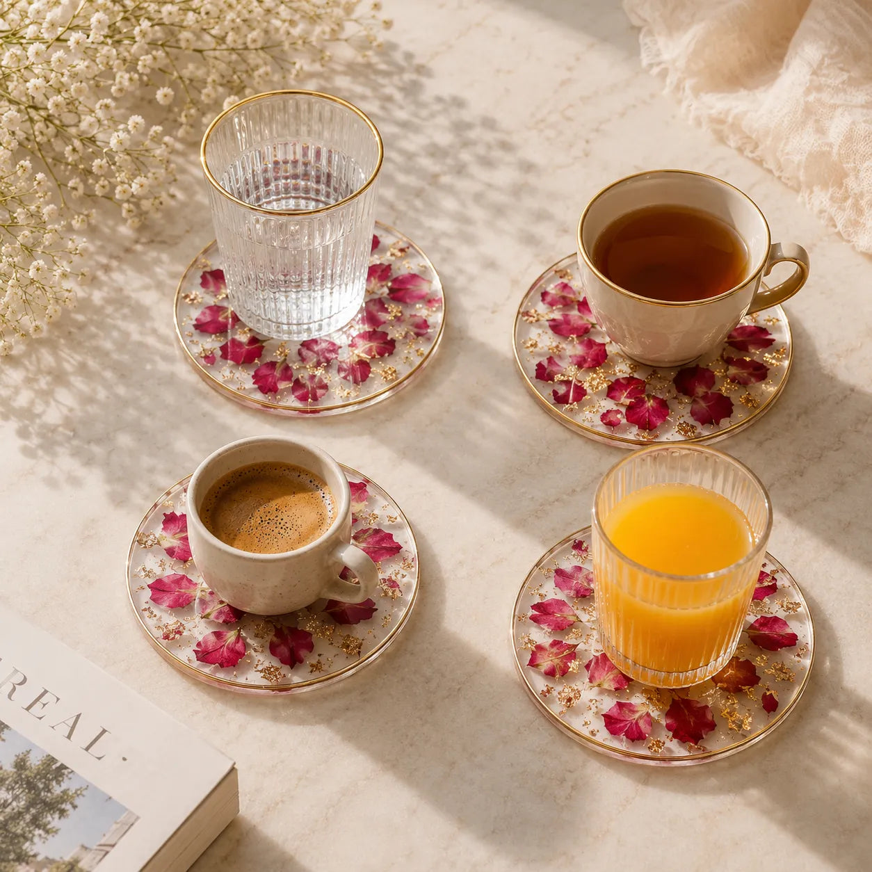 Cups of coffee, tea, and juice on floral coasters with a book and flowers in the background.