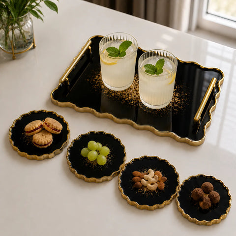 Two glasses of lemonade with mint leaves on a black tray, surrounded by small plates with snacks and fruits on a white surface.