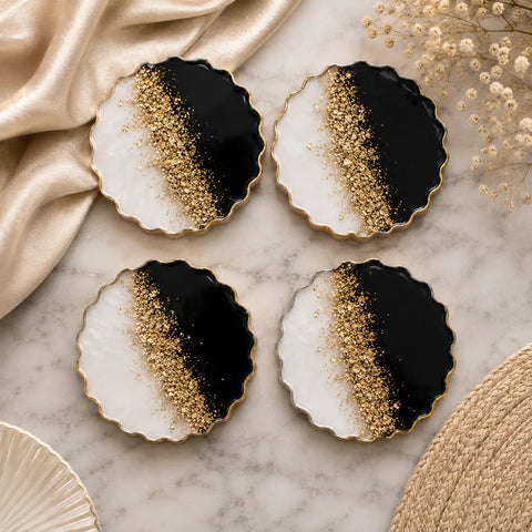 Four decorative plates with black and gold gradient design on a marble surface.