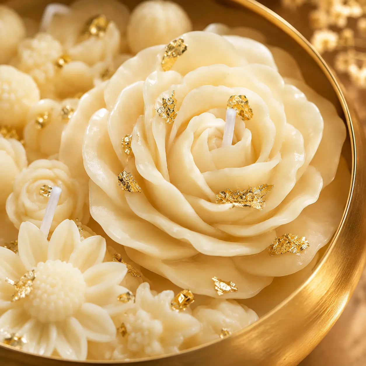Rose-shaped candles with gold accents on a gold plate
