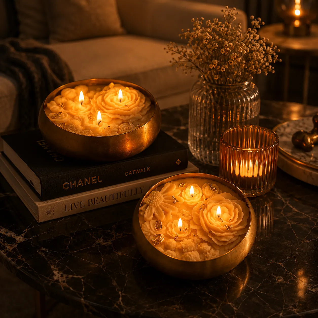 Decorative candles in floral holders on a table with books and a vase.