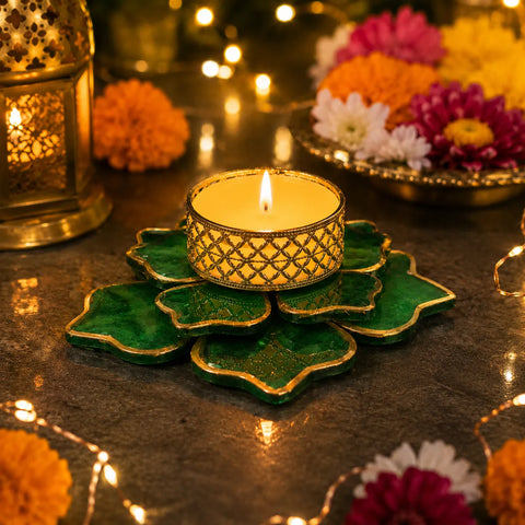 Decorative candle holder with a lit candle on a dark surface with flowers and lanterns in the background.