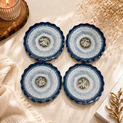 Four blue and white ceramic coasters on a textured surface with decorative elements.