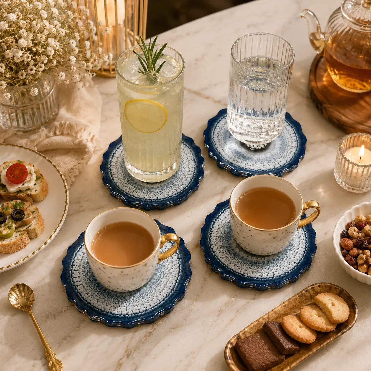 Tea set with cups, saucers, and snacks on a marble table.