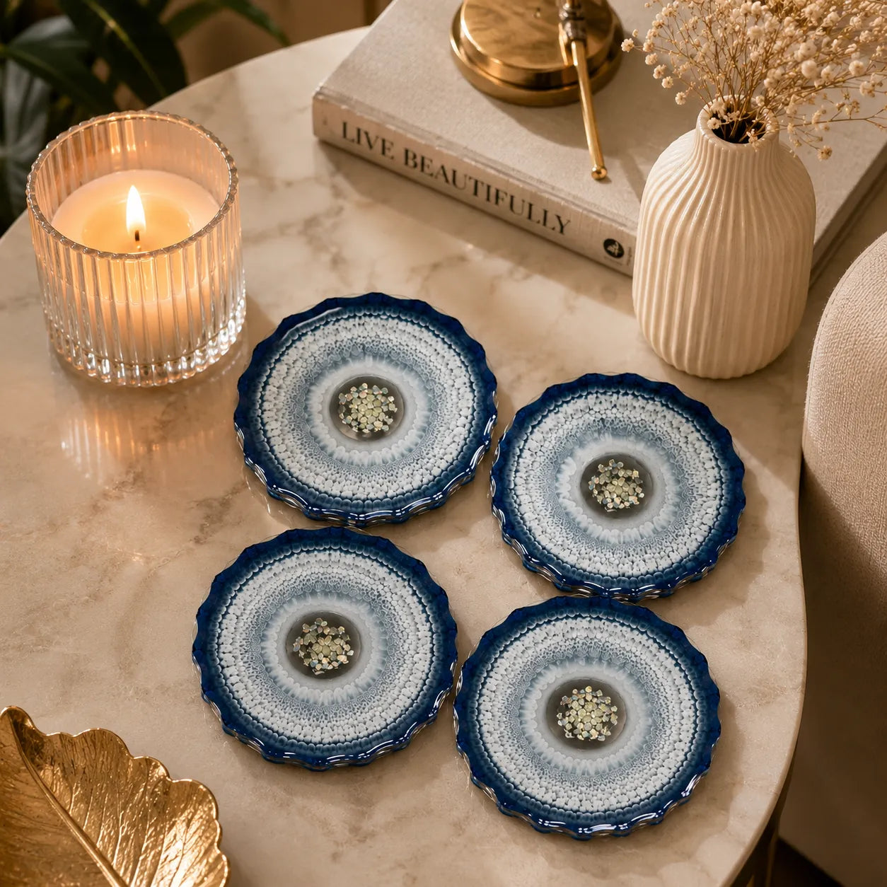 Set of four blue and white patterned coasters on a marble surface with a candle and decorative items.