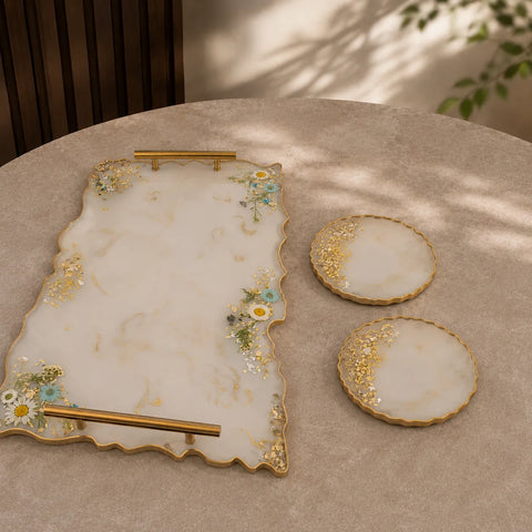 Cream marble resin serving tray with gold handles and matching round coasters featuring gold flakes, white daisy floral detailing, and luxury handmade glossy finish on a premium beige table setup.