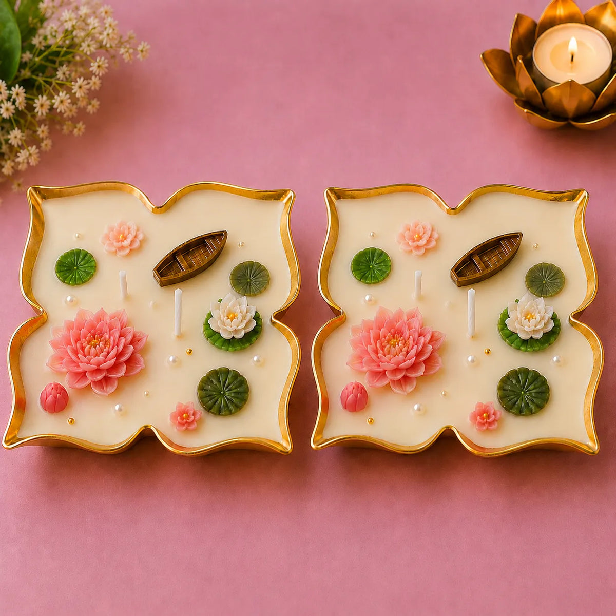 Two decorative candles with floral designs on a pink background
