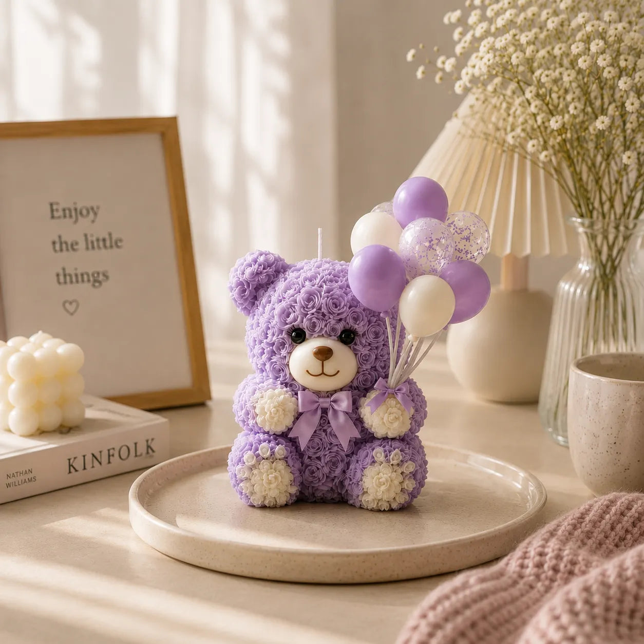 Purple teddy bear with balloons on a table with decor items