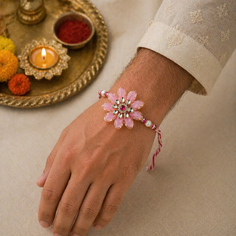 Hand wearing a pink floral bracelet with decorative elements, set against a neutral background.