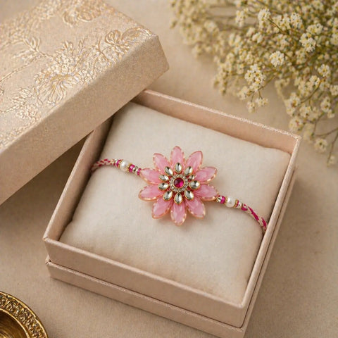 Pink floral bracelet with gemstones in a decorative box on a beige surface with flowers.