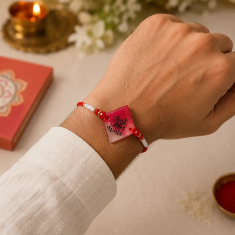 Hand wearing a red beaded bracelet with a pink heart-shaped tag, set against a festive background.