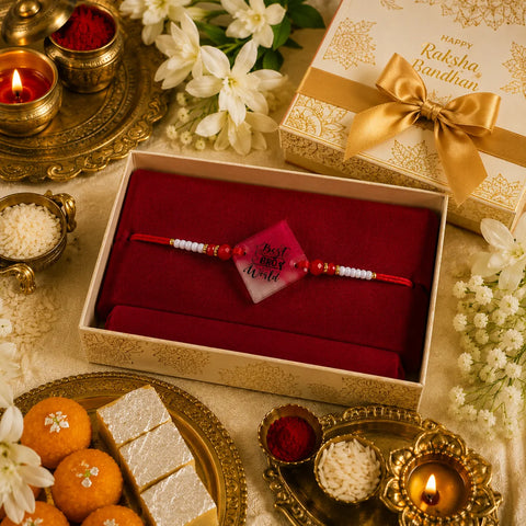 Rakhi with a card in a box surrounded by traditional items on a festive setting
