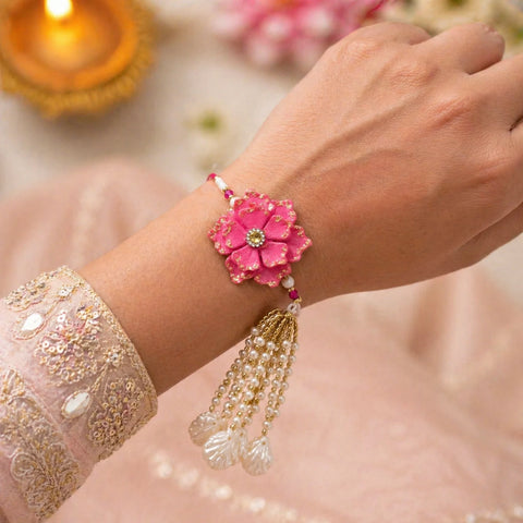 Hand wearing a pink floral bracelet with gold and pearl details, blurred background