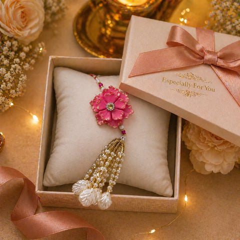 Pink floral jewelry with beads in a decorative box on a warm-toned surface with flowers and lights.