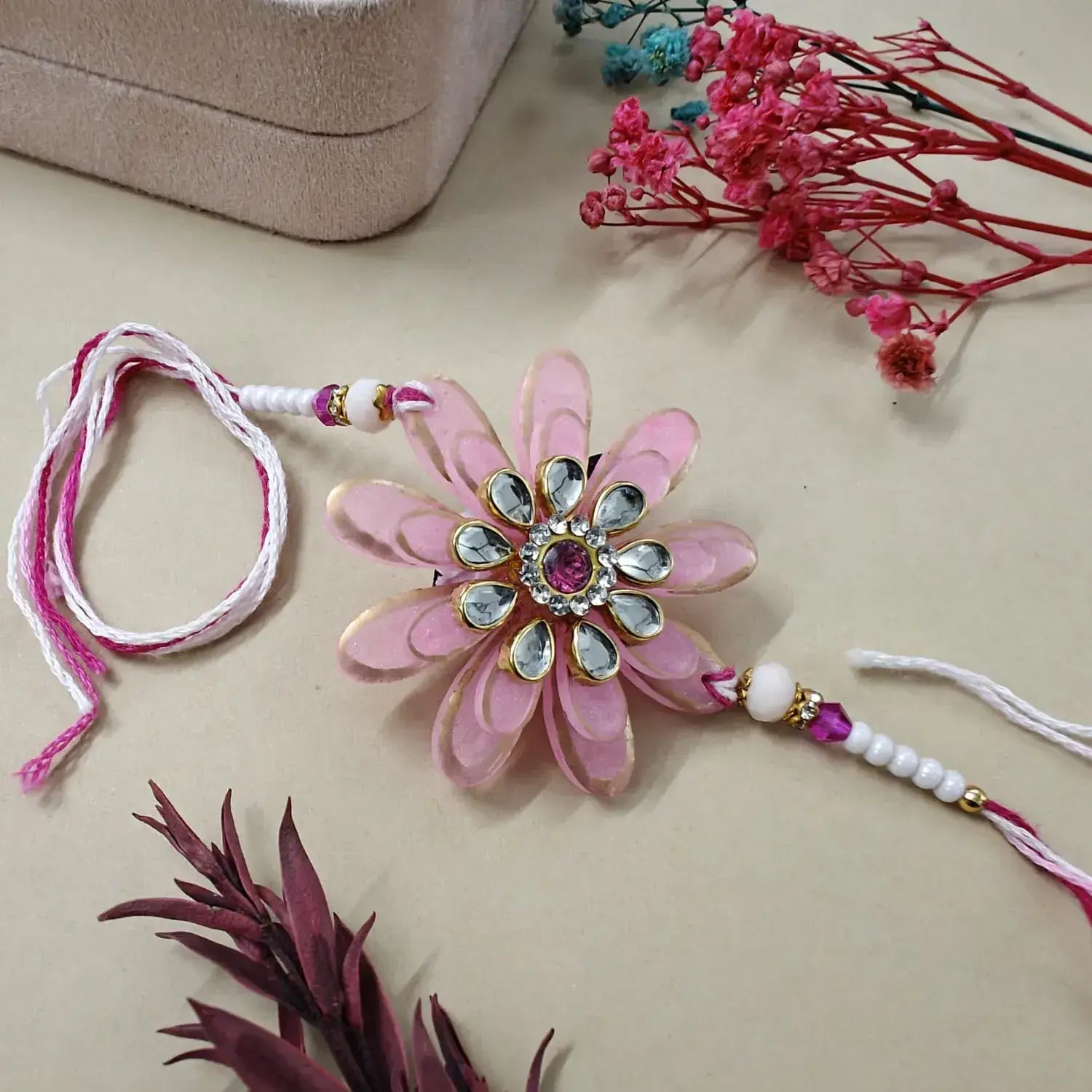 Decorative pink flower with gemstones on a beige surface with floral elements.