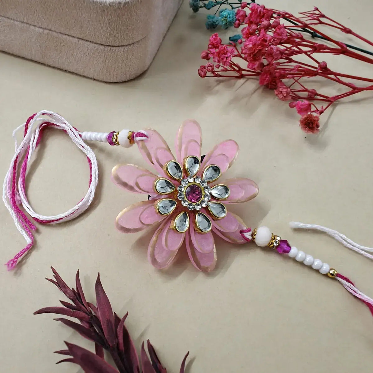 Decorative pink flower with gemstones on a beige surface with floral elements.