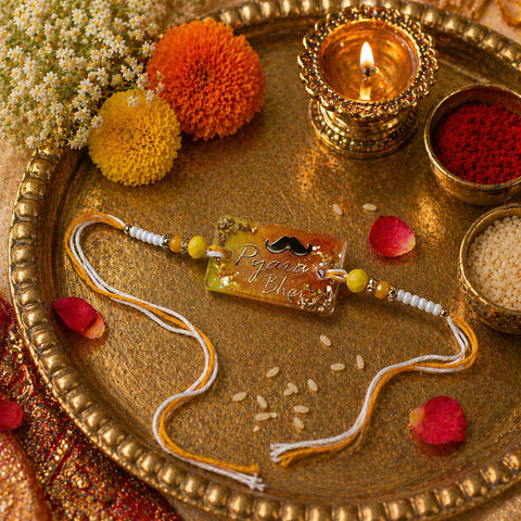 Decorative rakhi with beads on a gold tray with flowers and candles