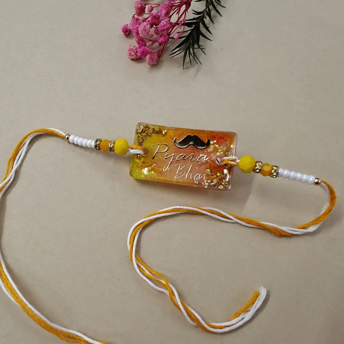 Decorative rakhi with text and beads on a beige background