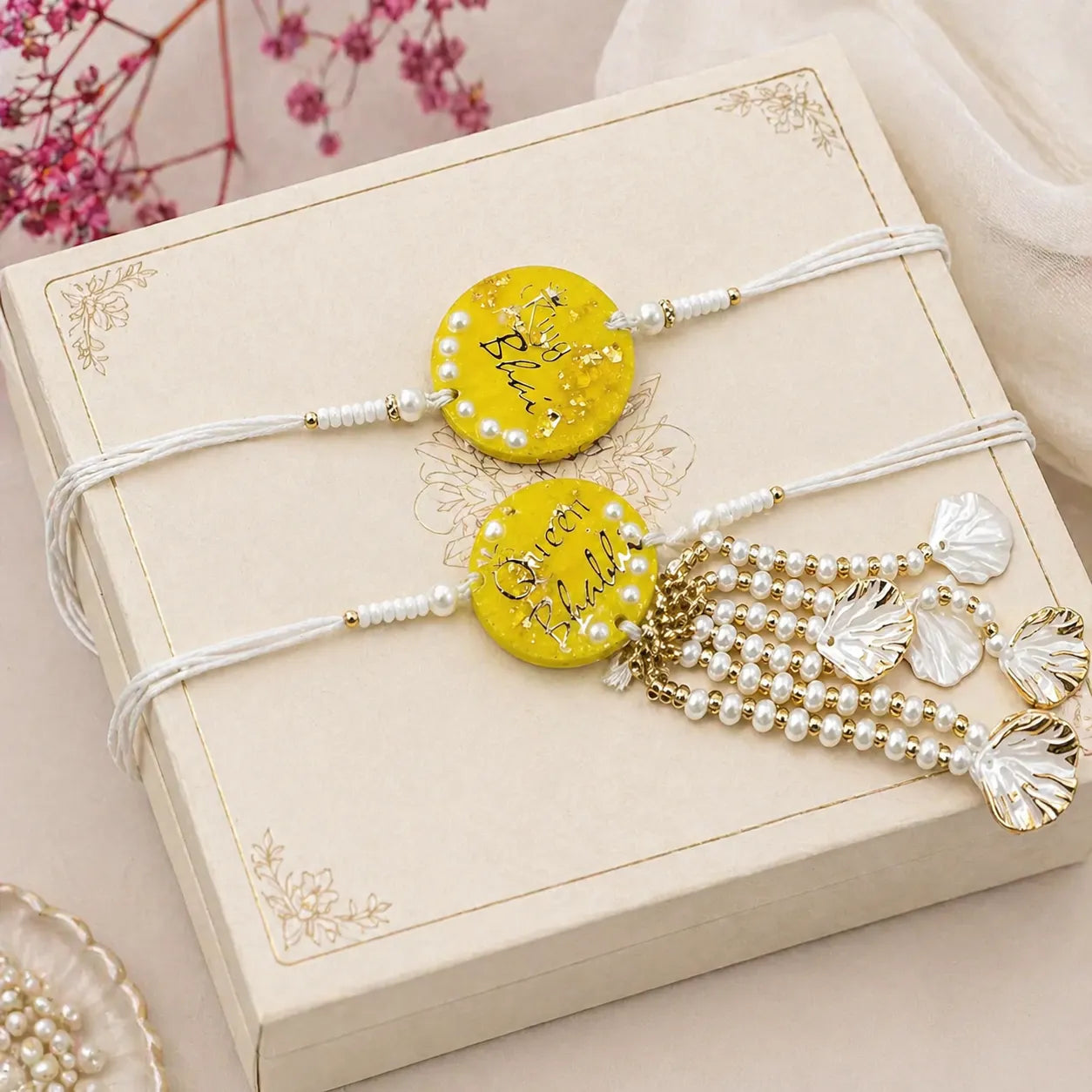 handmade yellow resin bhai bhabhi rakhi set with pearl lumba placed on gift box for raksha bandhan gifting
