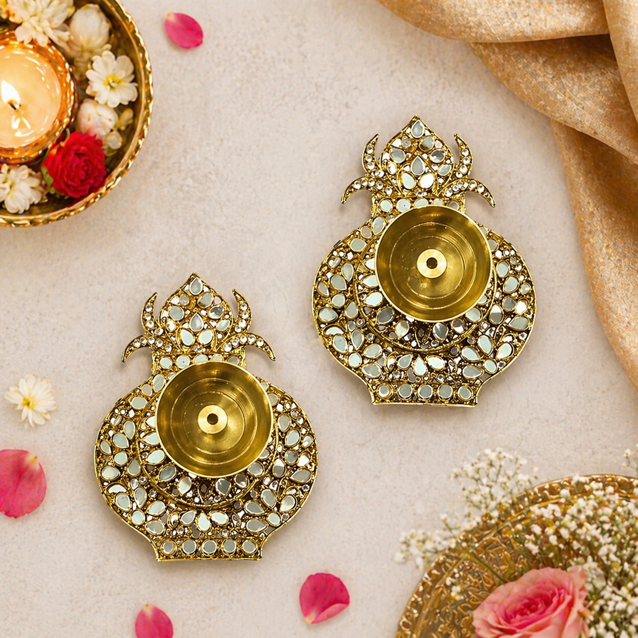 Decorative gold earrings with gemstones on a light background with flowers and candles.