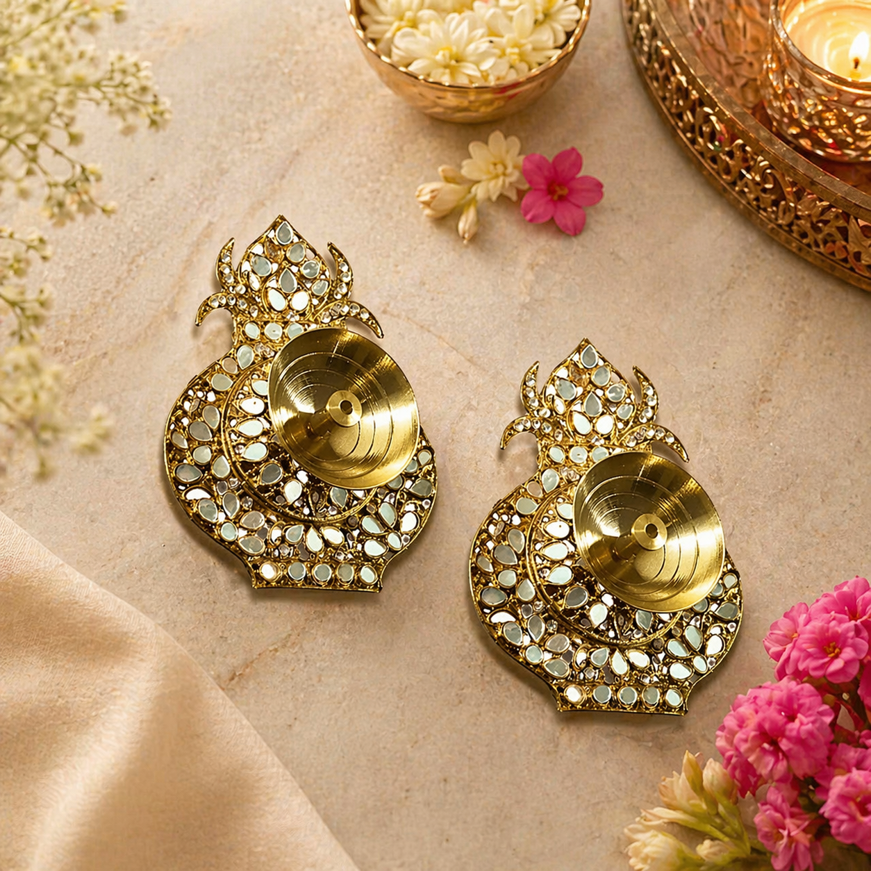 Decorative gold earrings with intricate designs on a beige surface with flowers.