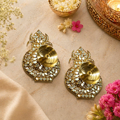 Decorative gold earrings with intricate designs on a beige surface with flowers.