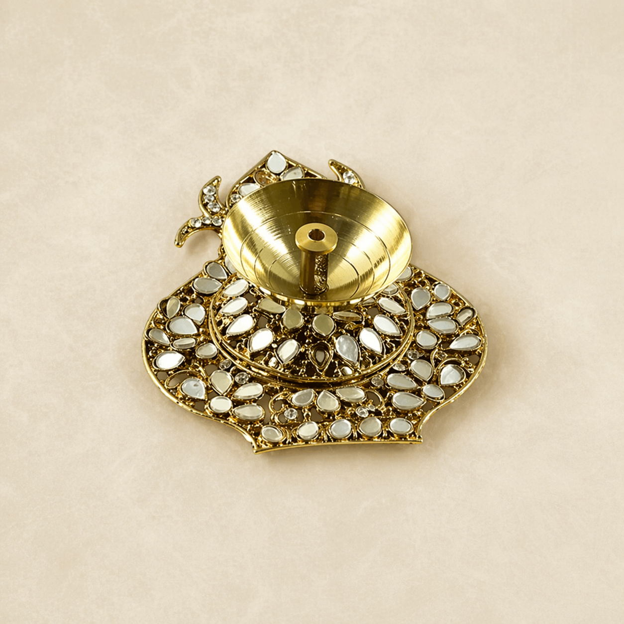 Gold decorative item with gemstones on a beige background