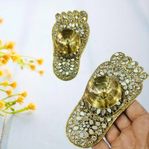 Decorative brass diya holders with intricate designs on a white background.
