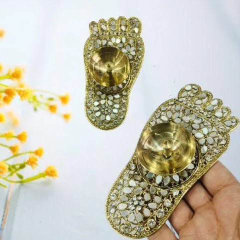 Decorative brass diya holders with intricate designs on a white background.