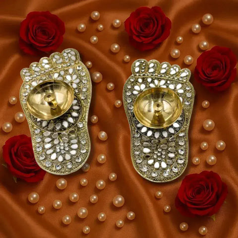 Decorative earrings with gold and silver details on a brown fabric background with red roses and pearls.