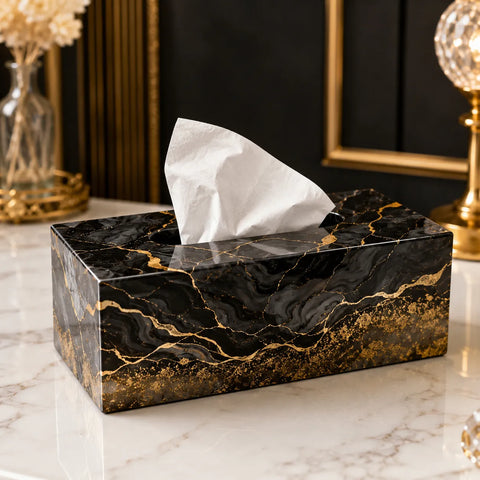 Black and gold marbled tissue box on a marble surface with decorative items in the background.