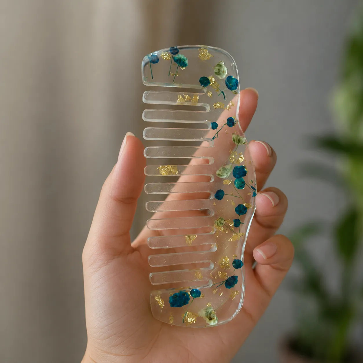 Clear comb with embedded flowers held by a hand against a neutral background