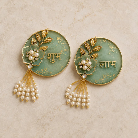Pair of decorative earrings with green circular design, gold accents, and pearl elements on a beige background.