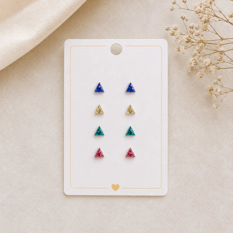 Set of triangle-shaped earrings on a display card with dried flowers on a beige background
