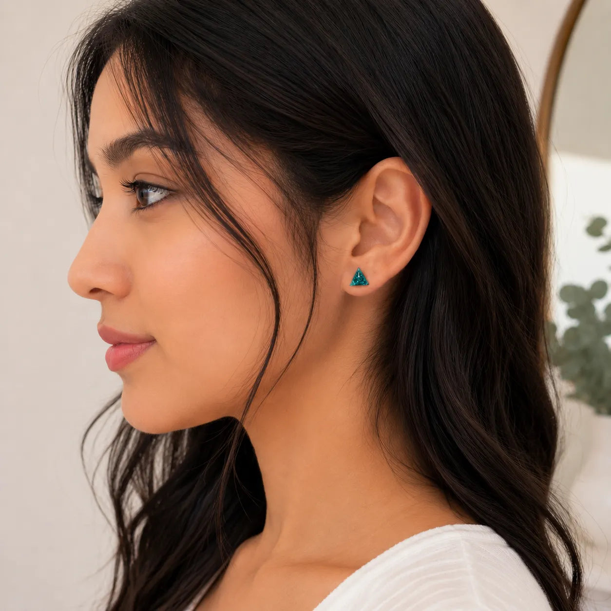 Close-up of a woman wearing a turquoise earring with a neutral background