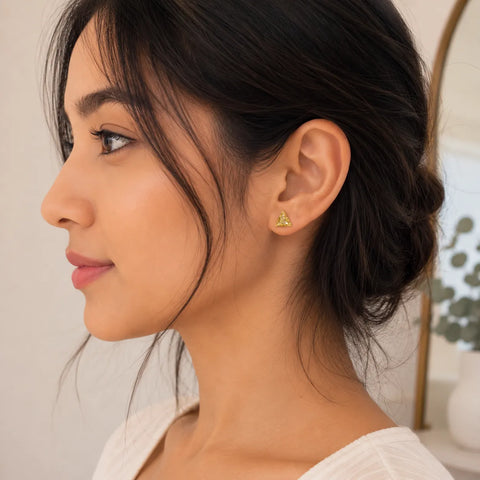 Close-up of a woman wearing a gold earring with a neutral background
