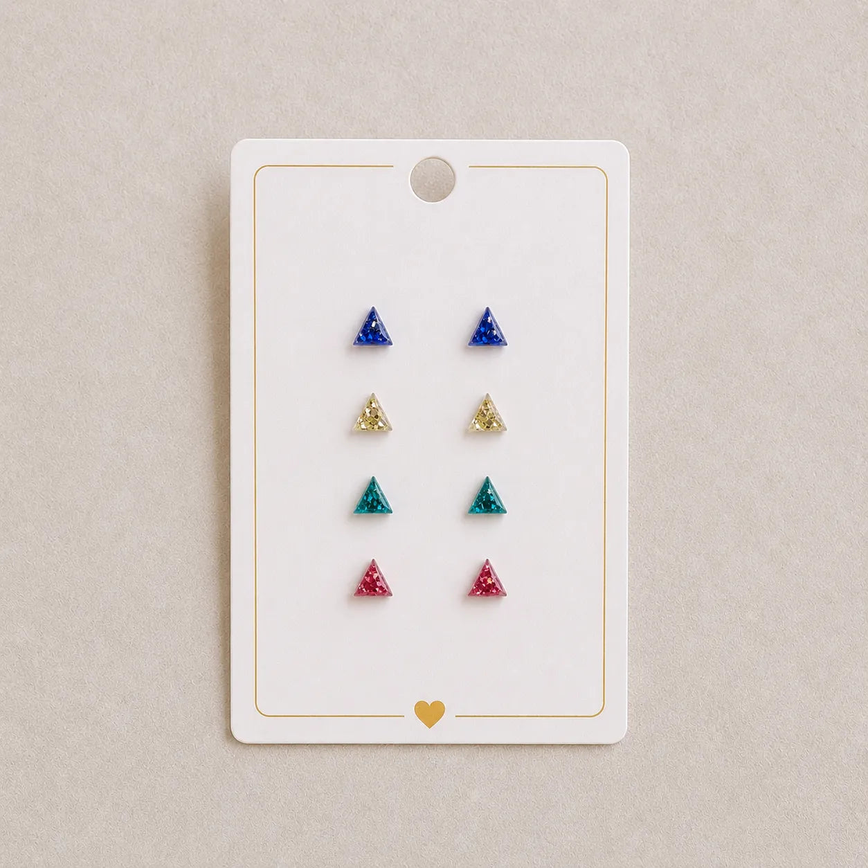Set of triangle-shaped earrings on a display card with a beige background