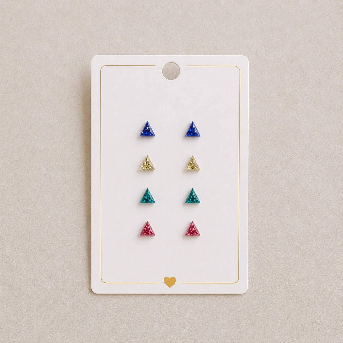 Set of triangle-shaped earrings on a display card with a beige background