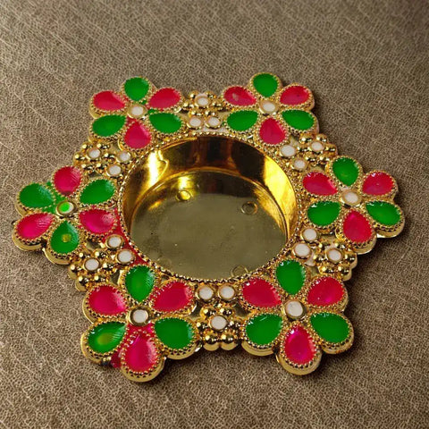 Decorative Diwali lamp with gold base and colorful flower-shaped design on a brown background