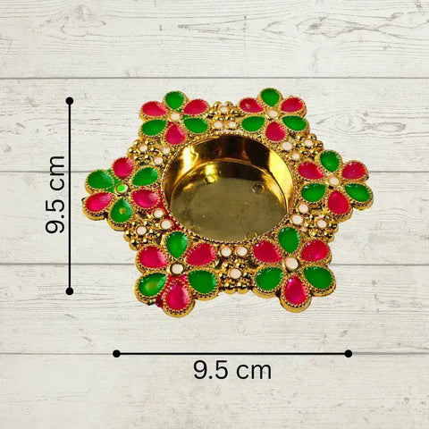 Decorative Diwali oil lamp with green and red accents on a light wooden surface