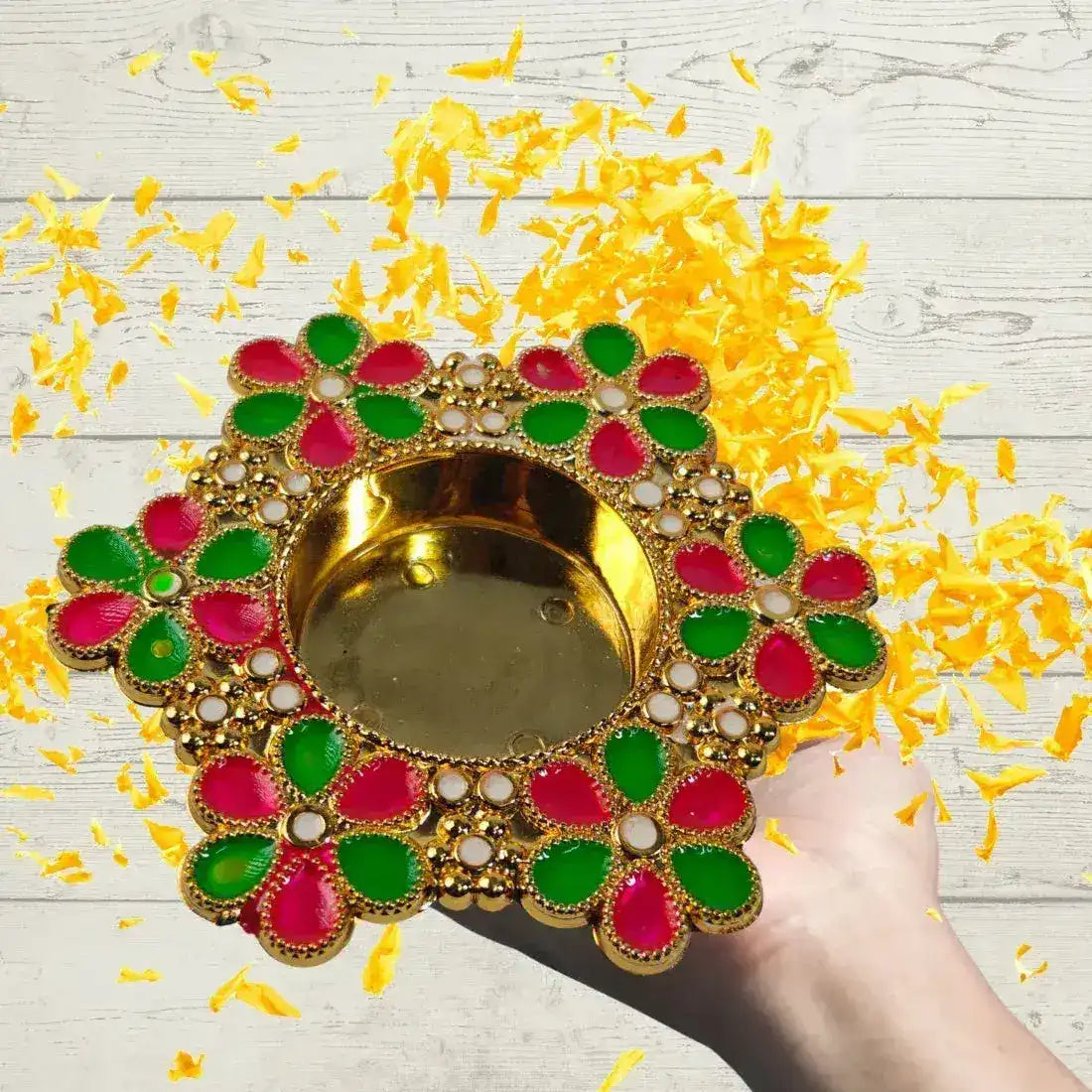 Decorative Diwali lamp with colorful design on a wooden surface with yellow decorative elements.
