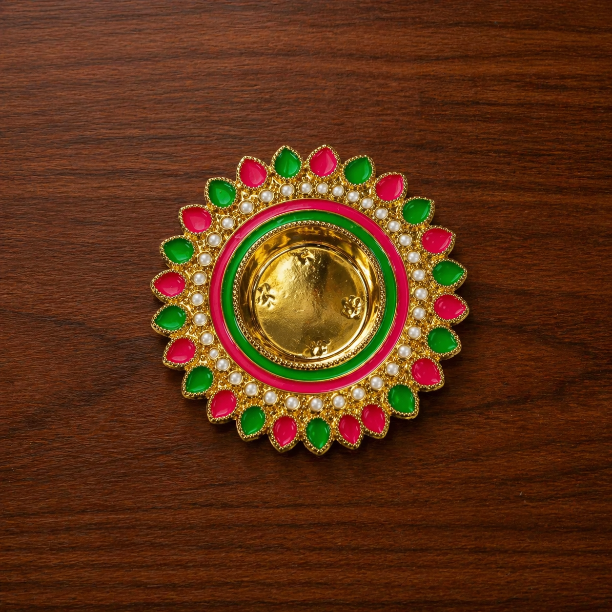 Decorative gold ring with pink and green accents on a wooden surface