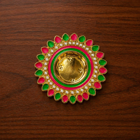 Decorative gold ring with pink and green accents on a wooden surface
