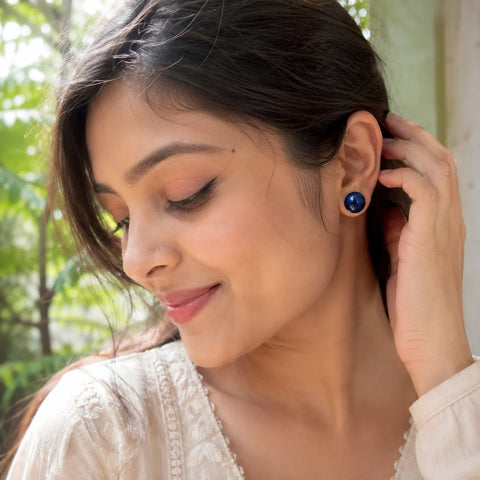 Indian woman wearing handmade navy blue glossy resin stud earrings with metallic shimmer finish in a natural daylight lifestyle fashion look