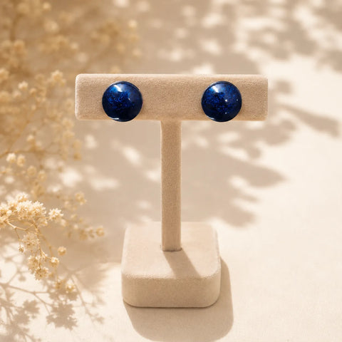 Handmade navy blue glossy resin stud earrings displayed on a beige velvet jewellery stand with metallic shimmer finish and premium minimal styling