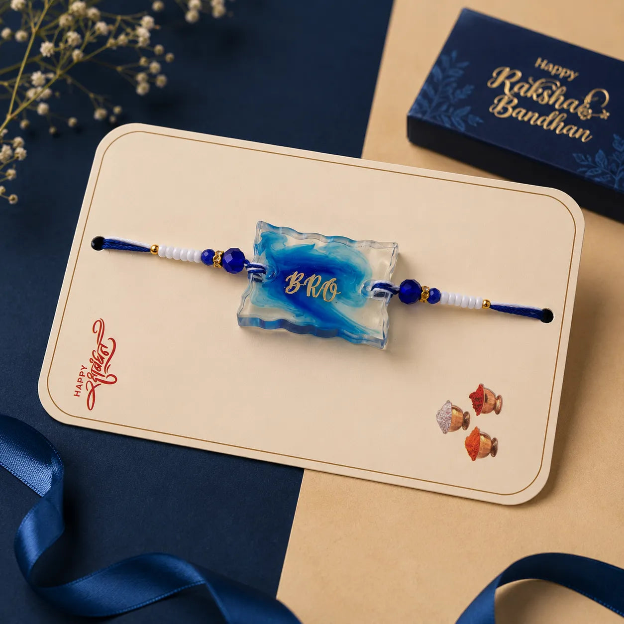 Two rakhi (holy threads) on a card with 'Happy Rakshabandhan' text, placed on a blue and beige background.